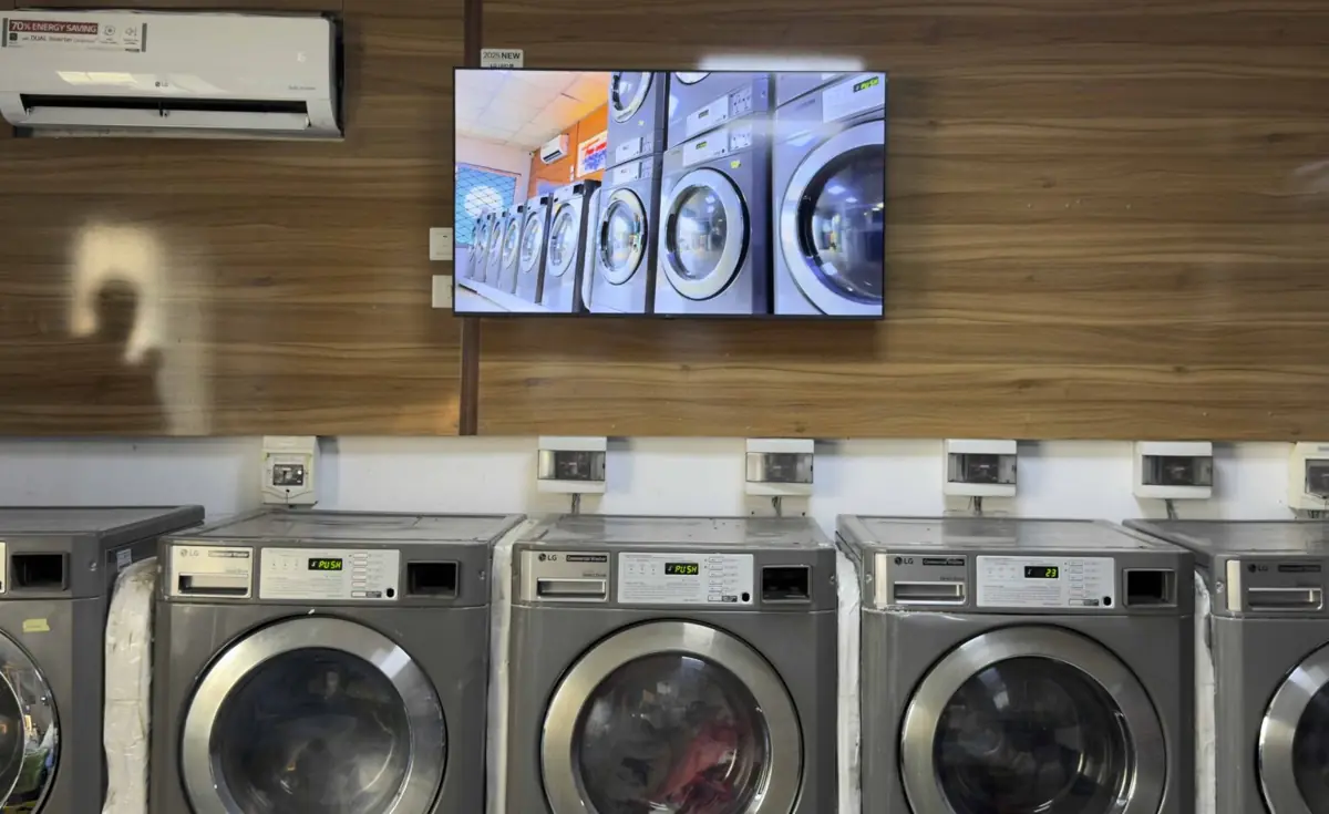 Digital signage screen in laundromat displaying content above washing machines
