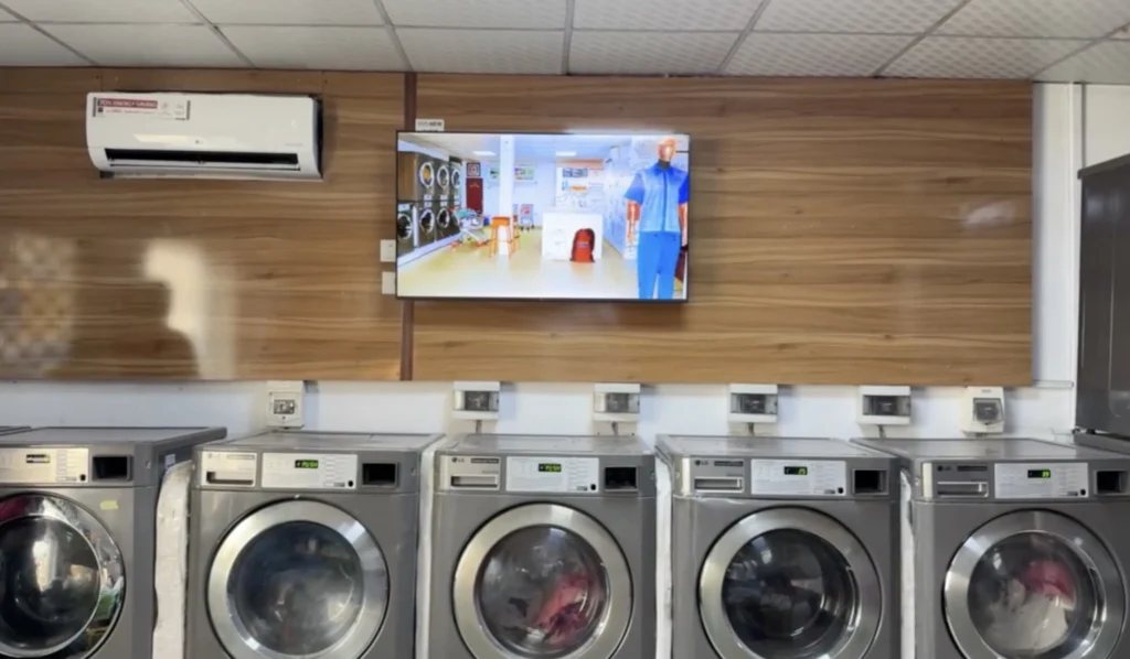 Example of digital signage implementation in a laundromat environment, where a screen displays dynamic content to engage visitors, promote services, and enhance customer experience during wait time.